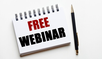 On a light background, a white notebook with the words FREE WEBINAR and a pen.