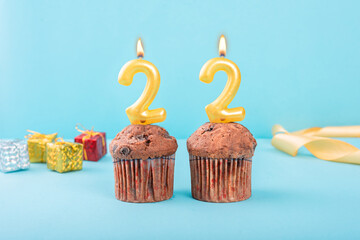 22 Number gold candle on a cupcake against a pastel blue background twenty two year celebration