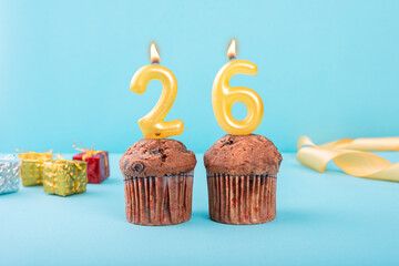 26 Number gold candle on a cupcake against a pastel blue background twenty six year celebration