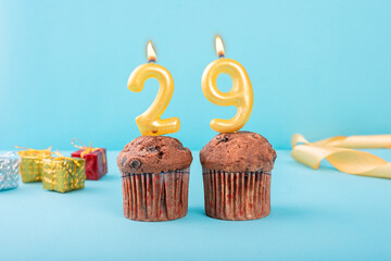29 Number gold candle on a cupcake against a pastel blue background twenty nine year celebration