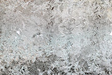 Glass covered with patterns and crystals of frost in winter