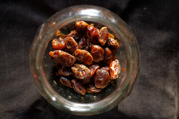 Suszone daktyle w dużym szklanym słoju na ciemnym tle