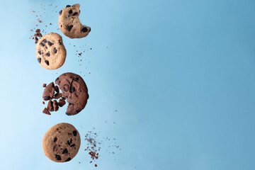 Four chocolate chip cookies flying on a blue background.