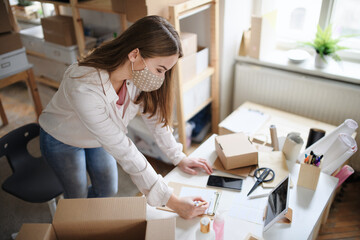 Young woman dropshipper with smartphone working at home, coronavirus concept.