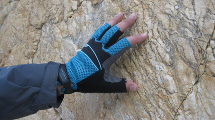 A hand in a sports glove touches a rock. Rock climbing. Mountaineering.