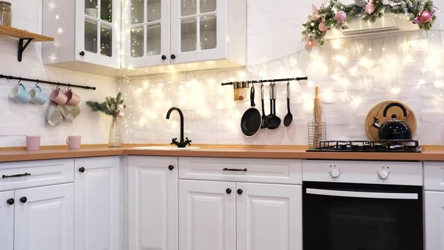 interior of white kitchen with pink decorated Christmas garlands .