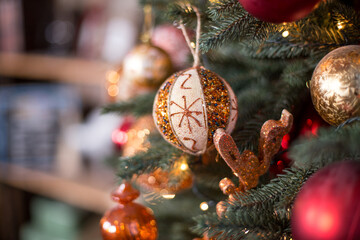 The New Year's tree with gifts and Christmas toys. Christmas tree and bokeh lights. Сhristmas ball and snowflake hanging on the tree. Decorated christmas tree.