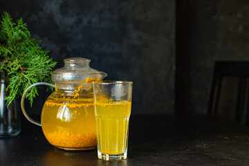tea sea ​​buckthorn in a teapot and  cup on the table christmas new year drink healthy meal ingredient top view copy space for tex