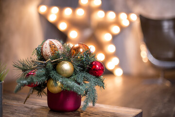 The New Year's little tree with Christmas toys at the table. Christmas tree and bokeh lights of the big star. Сhristmas ball and snowflake hanging on the tree. Decorated christmas tree.