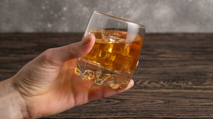 Glass of scotch whiskey in hand. Hand hold mug of scotch whisky. 