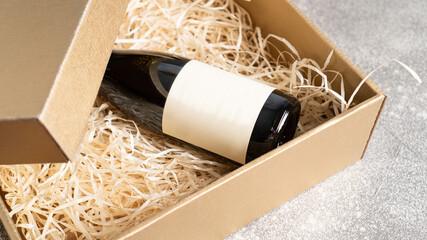 Present box with a bottle of wine with a blank label. Birthday present. Wine bottle in a wooden box with hay