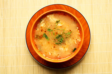 Bowl of chicken soup with spice, top view, bamboo table background