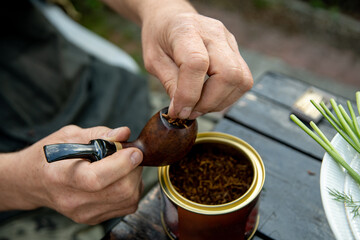hands put tobacco in the Smoking pipe