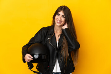 Fototapeta na wymiar Young caucasian woman holding a motorcycle helmet isolated on yellow background laughing