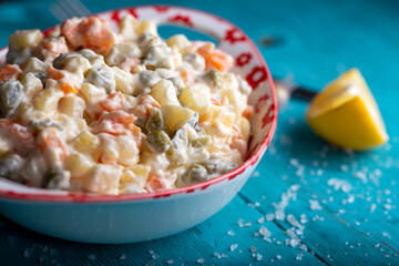 Bowl of traditional russian salad on blue wooden table. 