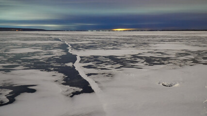 Lights of the night city over the frozen surface of the Voronezh reservoir in winter