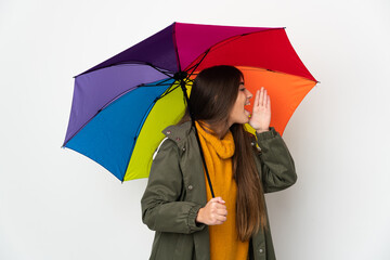 Young woman holding an umbrella isolated on white background shouting with mouth wide open to the side