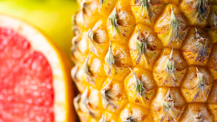 Whole pineapple and sliced grapefruit close up.