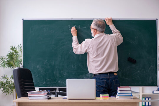 Old male teacher sitting in the classroom