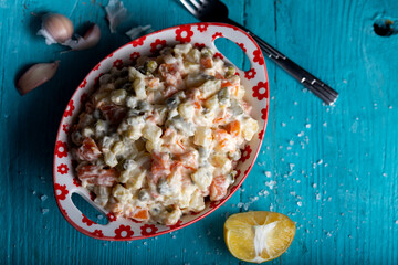 Bowl of traditional russian salad on blue wooden table. 