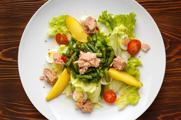 Classic Nicoise Salad On a white plate, on a dark wooden table