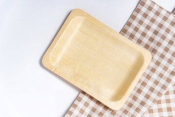 Top view of rectangular wooden dishes with plate on napkin on white table, template, copy space