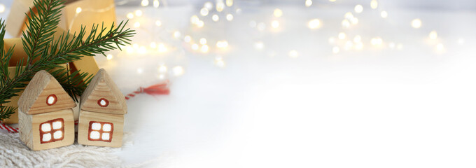 two wooden houses with light in the windows against the background of a fir branch with open gifts and illumination. winter home holidays