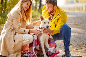 couple with dog walking. positive caucasian couple enjoy spending time with dog in the forest, at countryside. at sunny autumn day