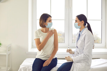 Professional nurse talking to a young woman who's about to get an antiviral vaccine