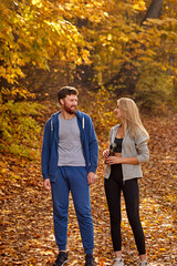 Fototapeta premium happy lovely couple enjoying walk in the forest, have talk after running, contemplate the nature, in casual sportive clothes. colorful yellow trees around