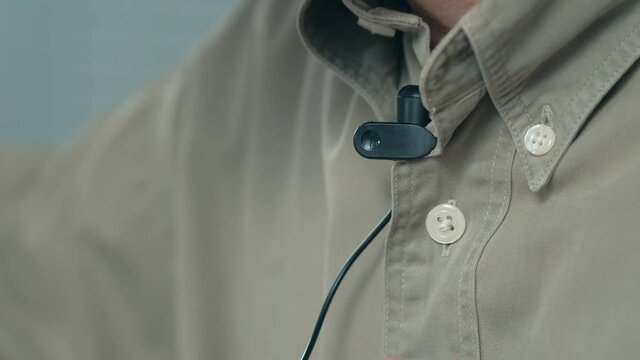 Attaching a lavalier lapel microphone to a shirt closeup shot.