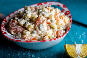 Bowl of traditional russian salad on blue wooden table. 