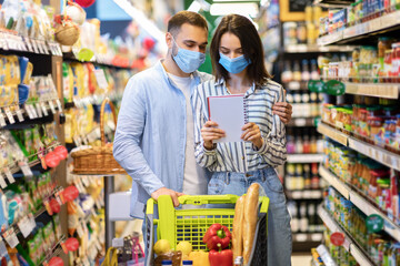Couple Wearing Face Masks In Hypermarket, Checking Shopping List