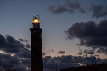 Lighthouse standing on the Dutch coast with a dramatic. and colorful dusk or dawn sky behind it. High quality photo