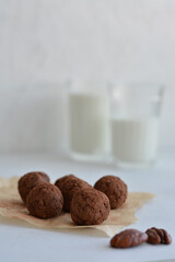 Energy balls. Homemade healthy raw energy balls with carob, figs decorated cocoa with glasses of milk on white background. Sugar free candies and  vegetarian truffles.