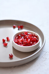 Pomegranate seeds on plate. Child's hand is grabing seeds of Pomegranate.