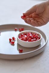 Pomegranate seeds on plate. Child's hand is grabing seeds of Pomegranate.