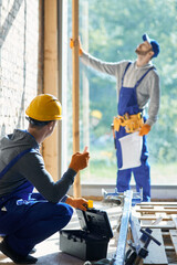 Renovate your house. Young male engineer working at cottage construction site, picking instrument...