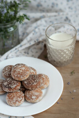 Honey cakes on a white plate with milk on a table with textiles