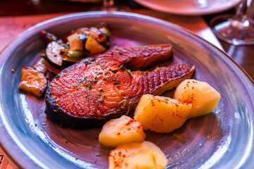 Red salmon spiced grilled steak with boiled potatoes and vegetables on a plate