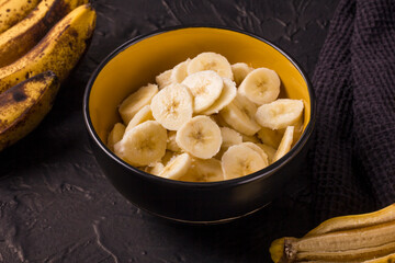 Round slices of ripe bananas in a deep plate on a dark background. Banana bread making process