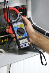 An electrical technician measures the voltage at the terminals using probes.Close up