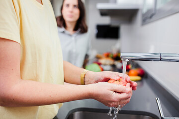 Women preparing healthy food and washing some vegetables in kitchen having fun, concept dieting nutrition.