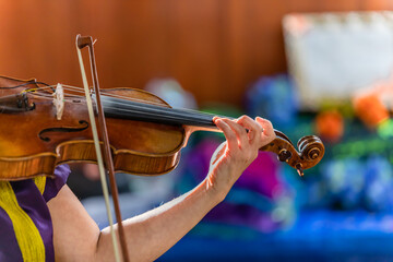 Selective focus of woman hands playing violin musical instrument with orchestra during the festival...