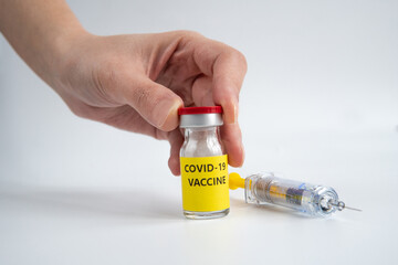 Hand is holding a vial vaccine and syringe. A covid-19 coronavirus vaccination concept. It use for prevention and immunization. Vaccine concept on white background.