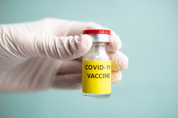 Hand with gloves is holding a vial vaccine on colorful background. Healthcare and Medical concept for covid-19. A covid-19 coronavirus vaccination concept. It use for prevention and immunization. 