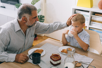 boy with his grandfather having breakfast at home