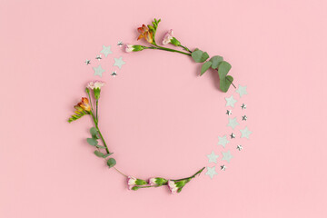 Obraz na płótnie Canvas Wreath made of confetti, flowers and eucalyptus on a pink pastel background. Floral frame with copy space.