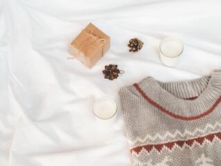 Cozy autumn or winter concept. candles, gift box with pine decoration, sweater on white background. minimal concept. top view, vintage 