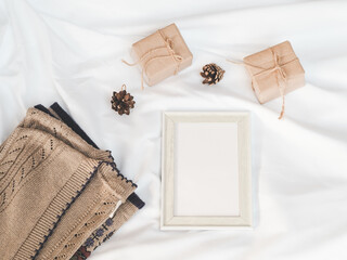 Cozy autumn or winter concept. white picture frame, gift box with pine decoration, sweater on white background. minimal concept. top view, vintage 